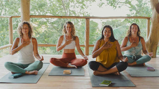 Women's retreat attendees sitting in lotus pose with their journals in a Costa Rica jungle